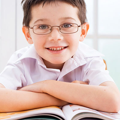 Smiling boy wearing glasses reading a book.